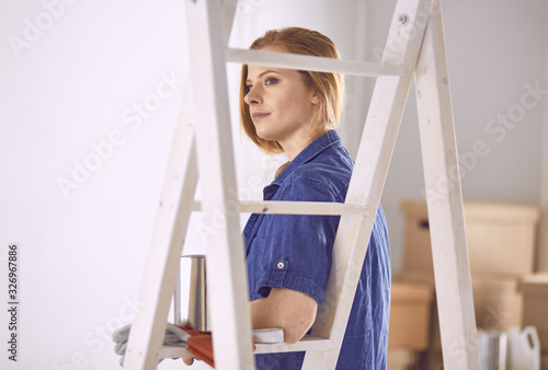 Beautiful young woman on a white wooden stepladder. Ready to repair the room. Women housework concept © lenetsnikolai