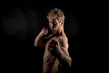 Beautiful muscles, athletic body. Studio photography on a black background, naughty light. Combat sport. Fair-haired sports man