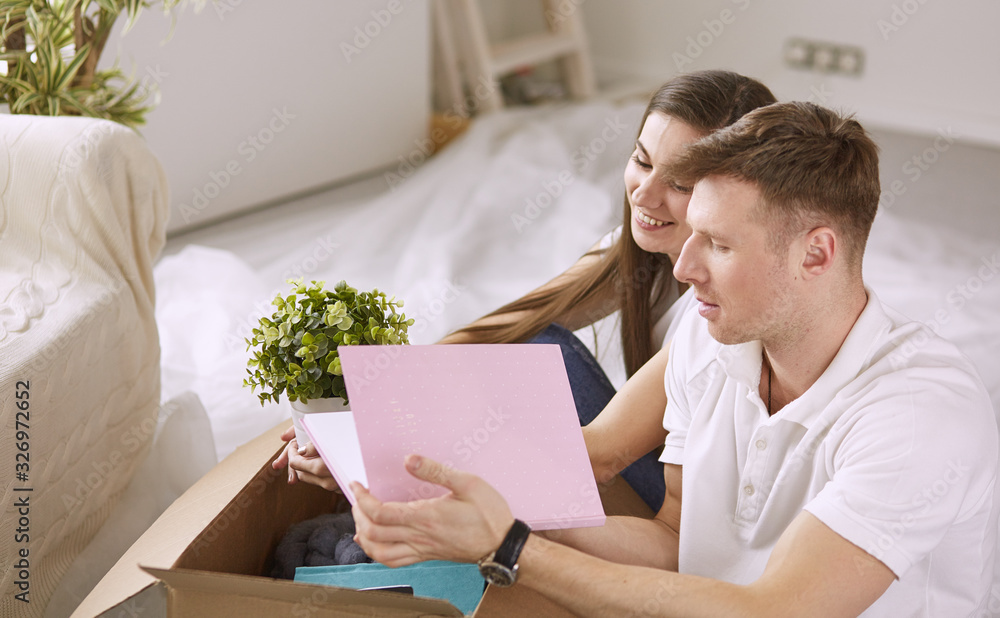 Portrait of happy couple looking at laptop computer together sitting in new house, surrounded with boxes Portrait of happy couple looking at laptop computer together sitting in new house, surrounded with boxes