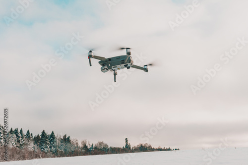 Fototapeta Naklejka Na Ścianę i Meble -  Small gray drone flying in the sky, quadcopter on a cloudy sky background.