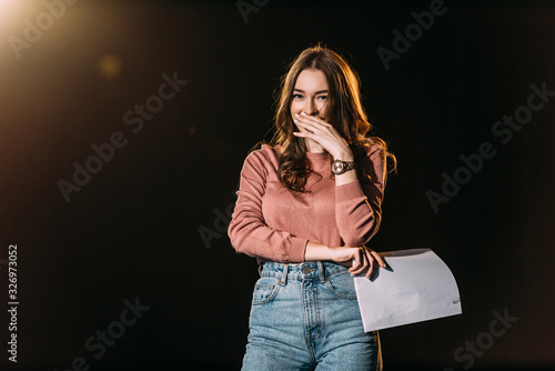 Foto laughing actress with screenplay on black with dramatic lighting