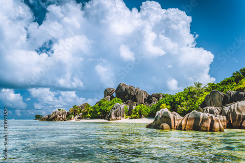 La Digue island, Seychelles. Beautiful vacation cloudscape on paradise Anse Source d'Argent beach with shallow blue lagoon, granite boulders in background