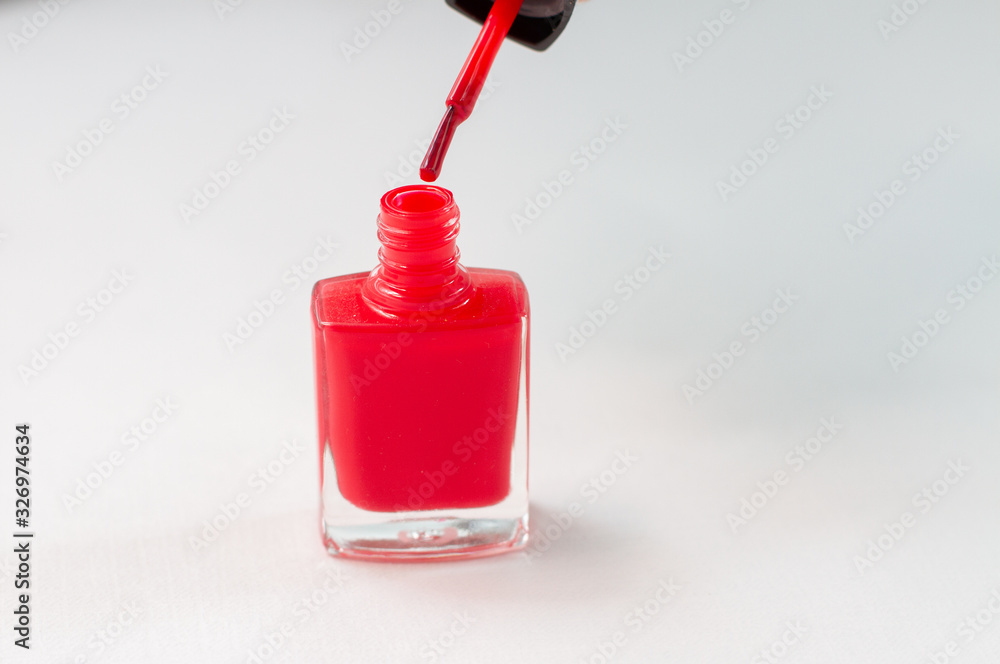 a red nail polish with a drop of brush on white background a red nail polish with a drop of brush on white background