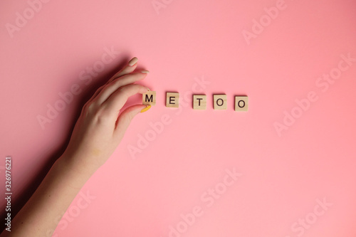 Woman hand making MeToo word with wooden alphabet on pink background, used for concept of sexual harrassment. photo
