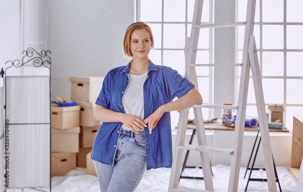 Beautiful young woman on a white wooden stepladder. Ready to repair the room. Women housework concept