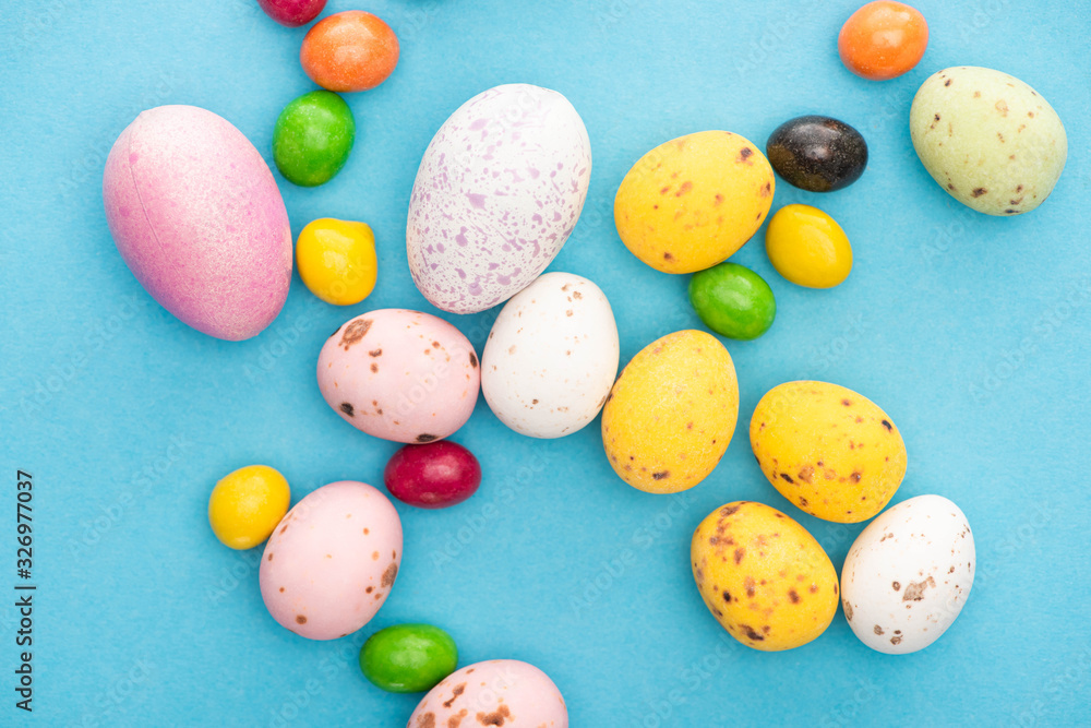 Top view of bright colorful sweets and easter eggs on blue background