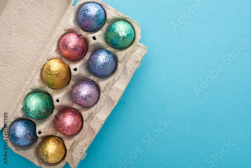 Top view of chocolate easter eggs in egg tray on blue background