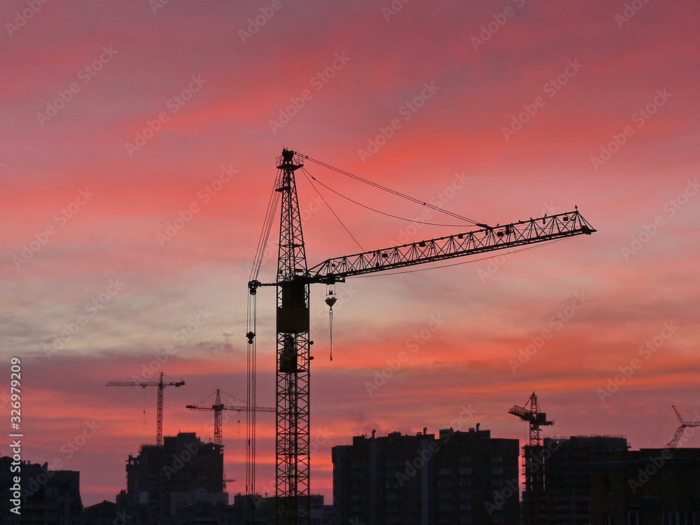 construction cranes against the background of bright evening clouds