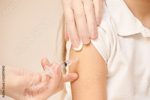 Doctor set shoulder injection to young pretty girl. Kid vaccine medical immunization. Cotton and syringe neat child arm. Medical hand. medicine pediatrician clinic. Sick baby. Copyspace. Horizontal