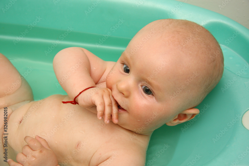 Baby bathing in a children's bath.. Close up portrait of a happy bathing baby Baby bathing in a children's bath.. Close up portrait of a happy bathing baby