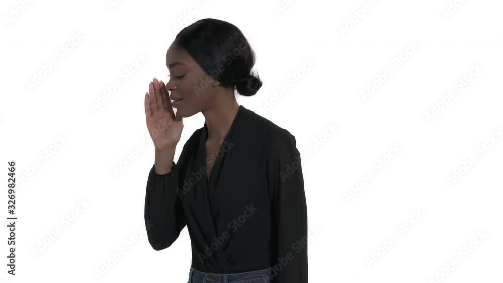 Charming young African woman gossiping. Close-up portrait of a model whispering and covering her mouth with hand. Body language. Isolated, on white background Charming young African woman gossiping. Close-up portrait of a model whispering and covering her mouth with hand. Body language. Isolated, on white background