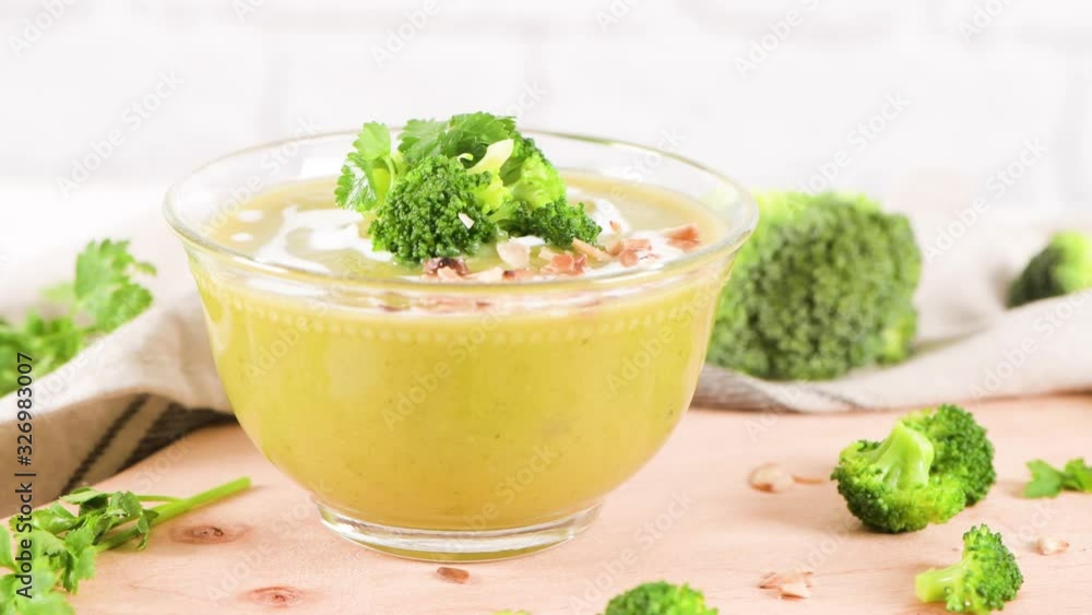 Broccoli soup in a glass bowl on a kitchen countertop with slices of the stems. Broccoli soup in a glass bowl on a kitchen countertop with slices of the stems.
