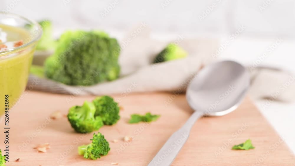 Broccoli soup in a glass bowl on a kitchen countertop with slices of the stems. Broccoli soup in a glass bowl on a kitchen countertop with slices of the stems.