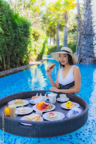 Portrait beautiful young asian woman happy smile with floating breakfast in tray on swimming pool © siraphol