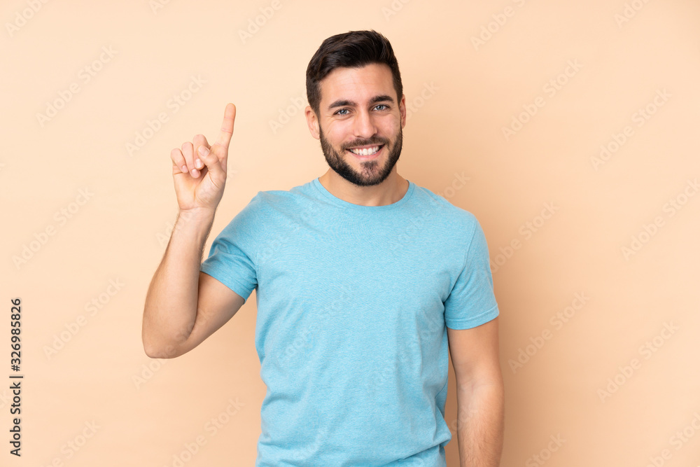 Caucasian handsome man isolated on beige background pointing up a great idea Caucasian handsome man isolated on beige background pointing up a great idea