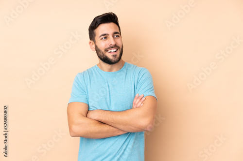 Caucasian handsome man isolated on beige background happy and smiling