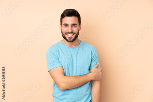 Caucasian handsome man isolated on beige background laughing