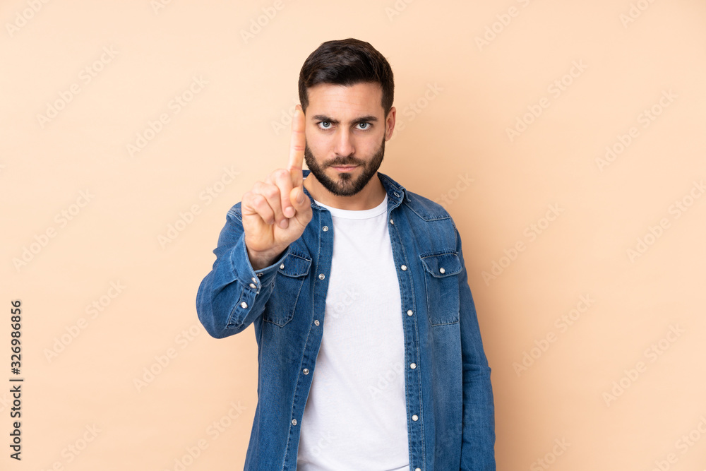 Caucasian handsome man isolated on beige background counting one with serious expression Caucasian handsome man isolated on beige background counting one with serious expression