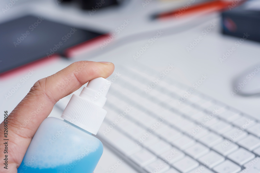 man disinfecting a computer keyboard man disinfecting a computer keyboard