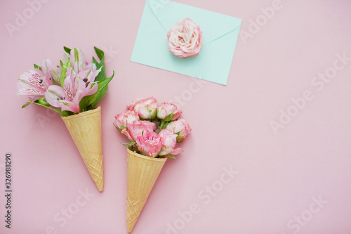 Fototapeta Naklejka Na Ścianę i Meble -  Ice cream cones with pink flowers and mint envelope on pink pastel background