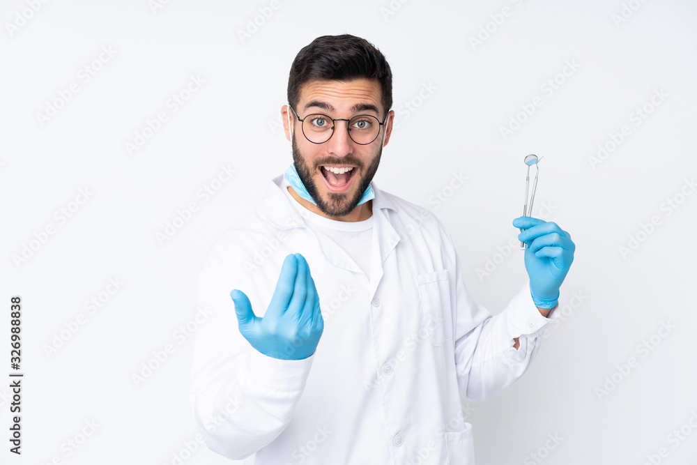 Dentist man holding tools isolated on white background inviting to come Dentist man holding tools isolated on white background inviting to come