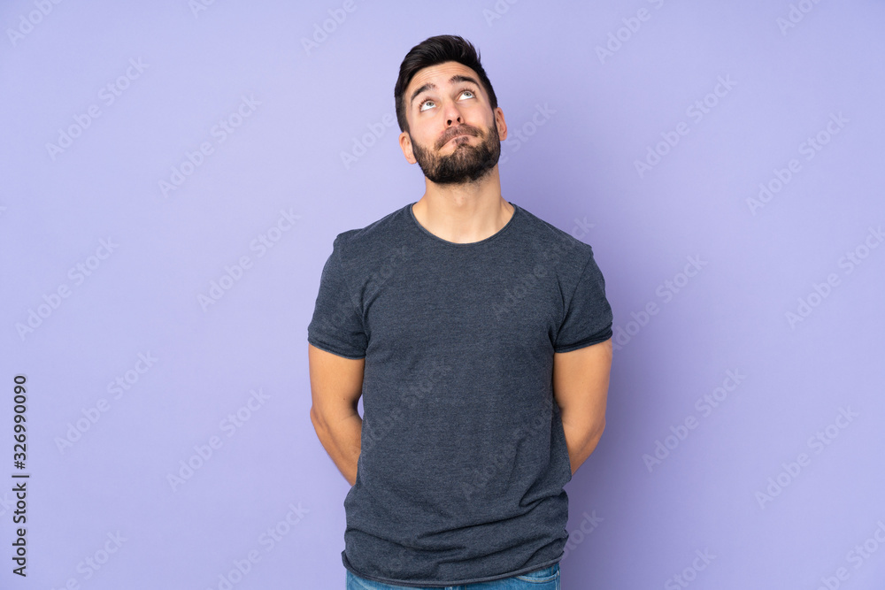 Caucasian handsome man and looking up over isolated purple background Caucasian handsome man and looking up over isolated purple background