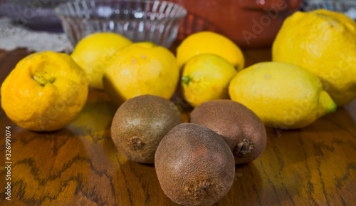 Tres kiwis y varios limones sobre una mesa de madera