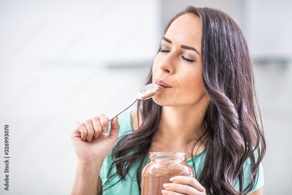 Young beautiful woman enjoys emotionally chocolate or hazelnuts cream