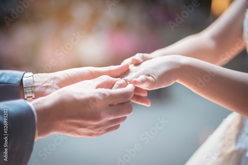 insert ring on the finger of women in the wedding time for the best memories in the life in the church in Thailand with bokeh background under the light 