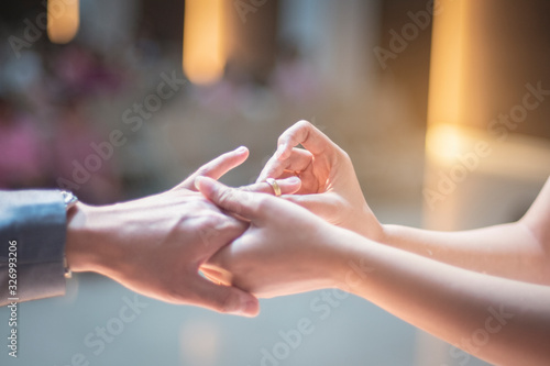 insert ring on the finger of women in the wedding time for the best memories in the life in the church in Thailand with bokeh background under the light 