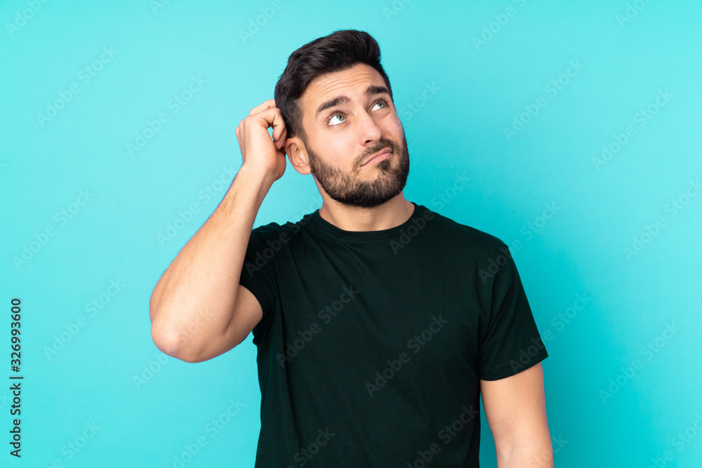 Caucasian handsome man isolated on blue background having doubts and with confuse face expression Caucasian handsome man isolated on blue background having doubts and with confuse face expression