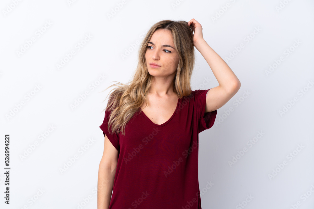Young woman over isolated white background having doubts while scratching head Young woman over isolated white background having doubts while scratching head
