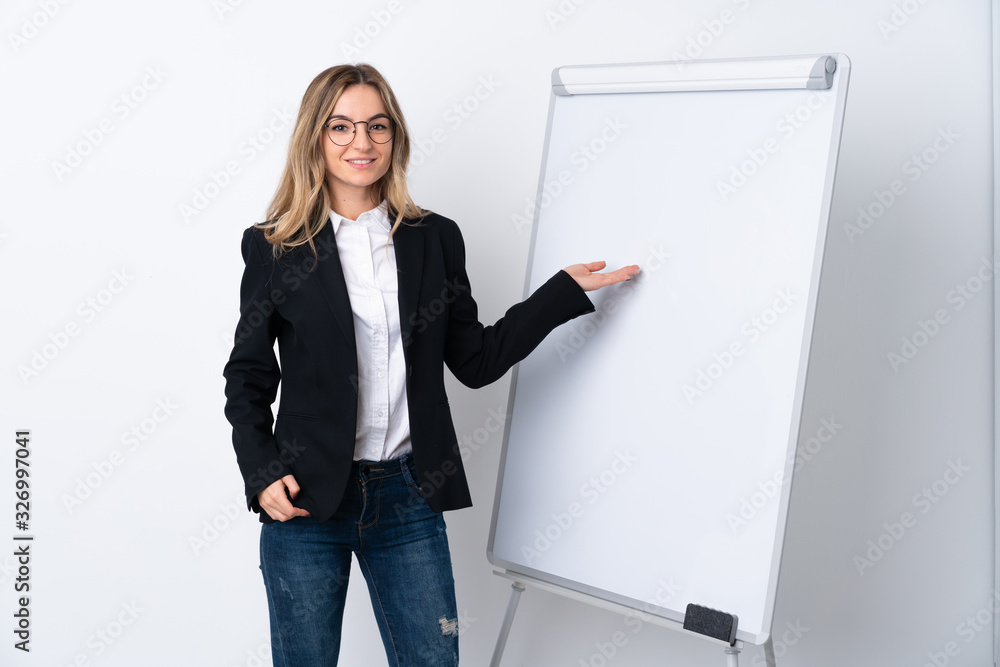 Young woman over isolated white background giving a presentation on white board and pointing it Young woman over isolated white background giving a presentation on white board and pointing it