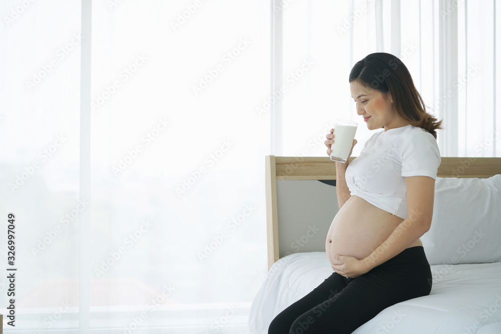 Asian pregnant woman drinking milk in the room Asian pregnant woman drinking milk in the room