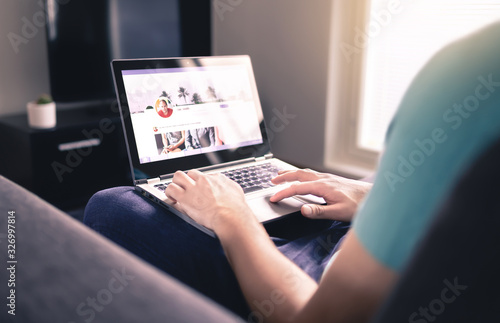 Social media profile on screen. Man using laptop at home. Personal online page. Business network website mockup. Writing status update. Follow, like or share post. Digital communication portal.