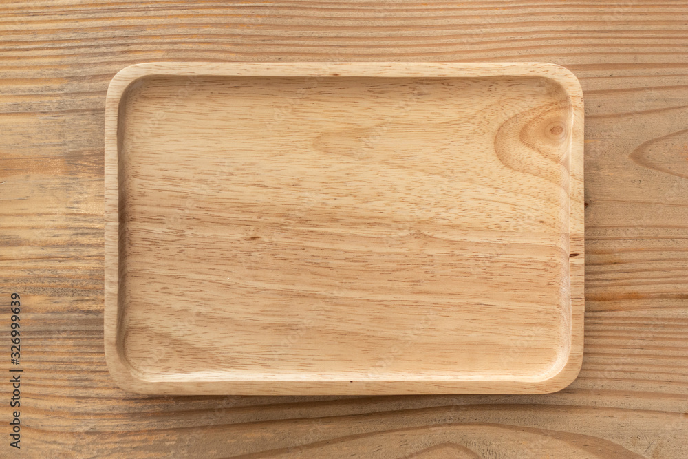 An empty wooden tray placed on a wooden table. An empty wooden tray placed on a wooden table.
