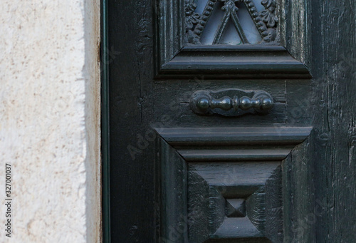 Wooden dark aged textured entrance with rings door handles and metal details. Architecture background. Old wooden door with rivets and aged metal door handle 