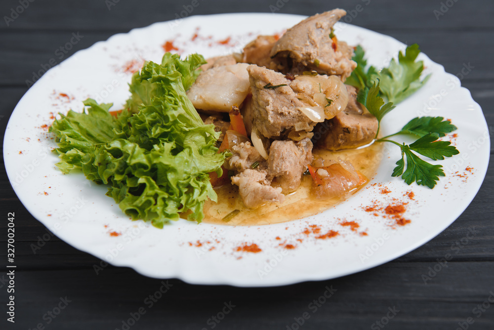 Plate of grilled beef nuggets, fried potato chips or French fries and fresh leafy green salad with cucumber on a white background