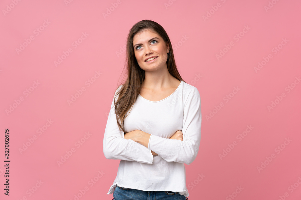 Young woman over isolated pink background looking up while smiling Young woman over isolated pink background looking up while smiling
