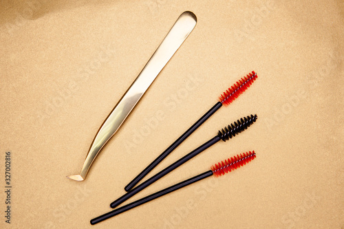  eyelash extension tools, golden tweezers and red-black brushes on a gold background