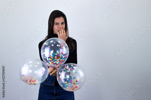 Con miedo mordiendose las uñas ballet dancer, caucasian middle age womanparty balloonsfeels fear, bits nails, isolated on gray background studio shot, black sweater, denim jacket, jeans, dark air. Pla