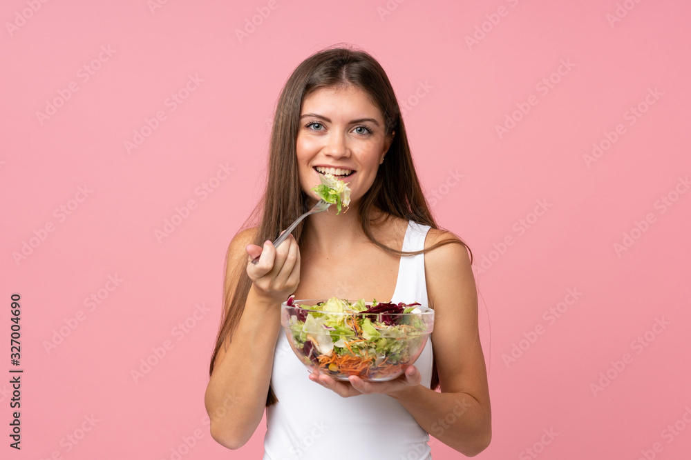 Young woman with salad over isolated pink wall