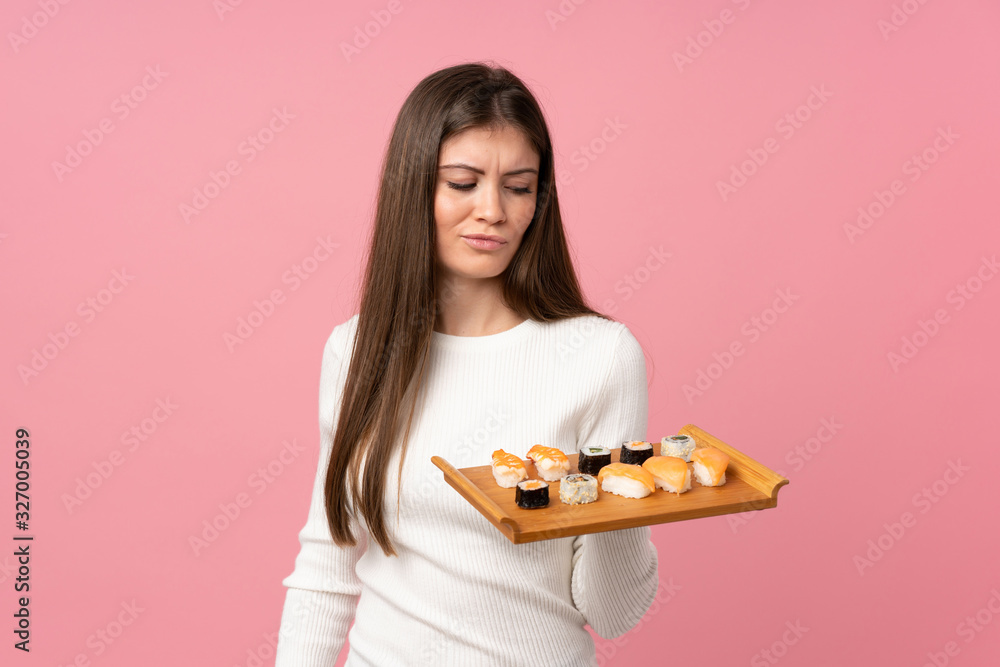 Young girl with sushi over isolated pink background with sad expression Young girl with sushi over isolated pink background with sad expression