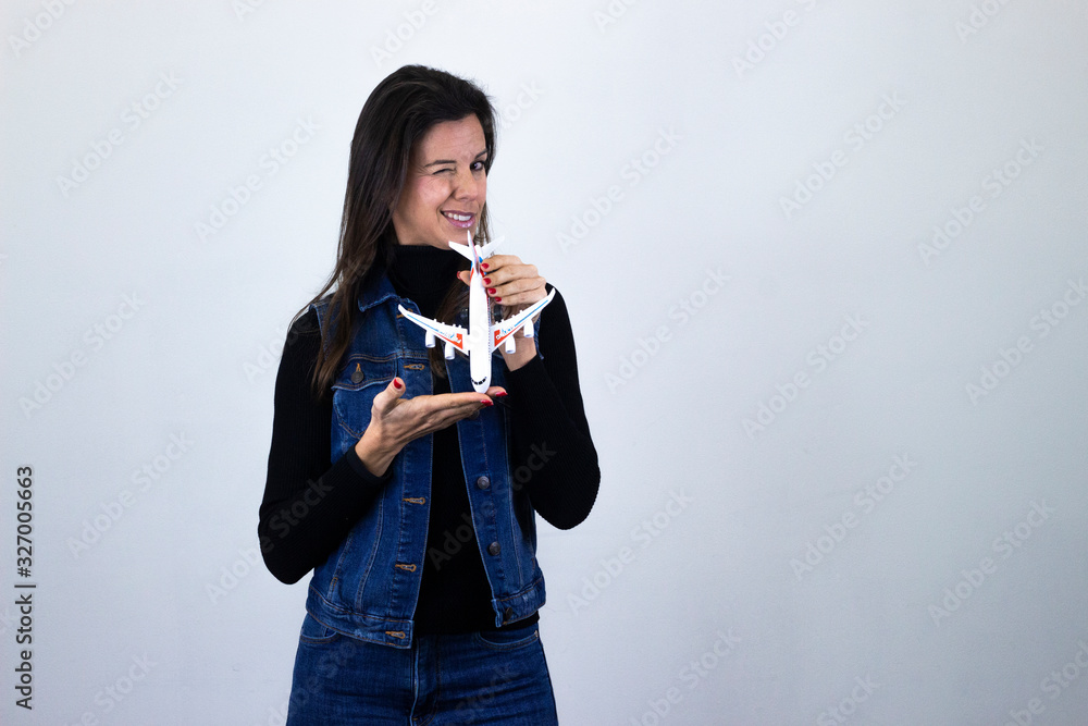 Portrait of happy middle age woman modelplane winking an eye, isolated on gray background studio shot, black sweater, denim jacket, jeans, dark air. Place for your text in copy space. Portrait of happy middle age woman modelplane winking an eye, isolated on gray background studio shot, black sweater, denim jacket, jeans, dark air. Place for your text in copy space.