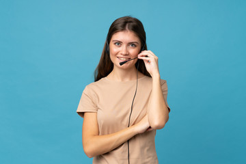 Young woman over isolated blue background working with headset