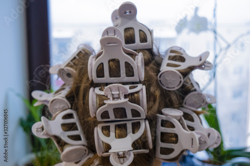 Curling rollers in a woman's hair. Hair curlers on the girl's head close up