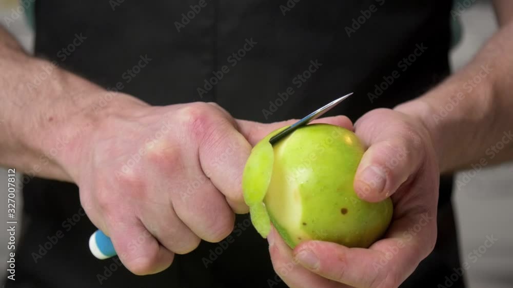 Man hands peeling green apple in slow motion Man hands peeling green apple in slow motion