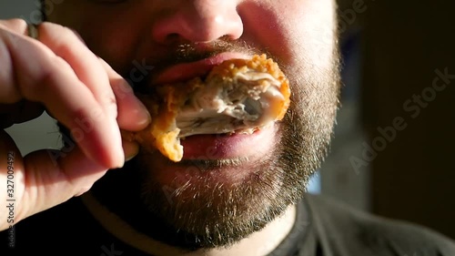 Fat man with a thick beard eats chicken nuggets, harmful and tasty fast food, close-up