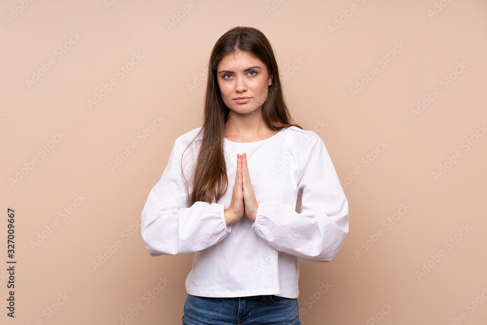 Young girl over isolated background keeps palm together. Person asks for something Young girl over isolated background keeps palm together. Person asks for something