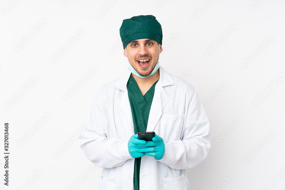 Surgeon in green uniform isolated on isolated white background surprised and sending a message Surgeon in green uniform isolated on isolated white background surprised and sending a message
